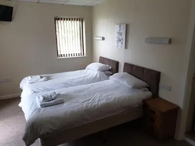 two beds in a room with white sheets and a window at Neuadd Henllan Lodge in Builth Wells