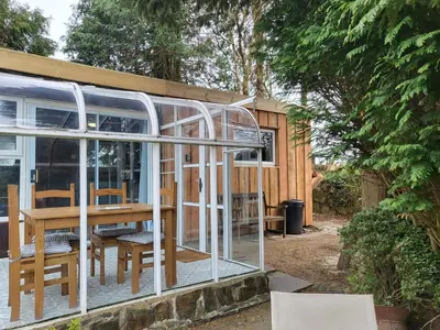 a glass house with a table and chairs in it at Indigo Lodge - Aberdovey in Aberdyfi