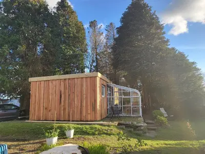a small wooden building in a yard with trees at Indigo Lodge - Aberdovey in Aberdyfi