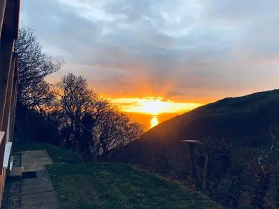 a sunset with the sun setting on a hill at Indigo Lodge - Aberdovey in Aberdyfi