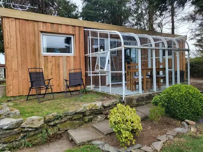 a small house with two chairs and a lot of glass at Indigo Lodge - Aberdovey in Aberdyfi