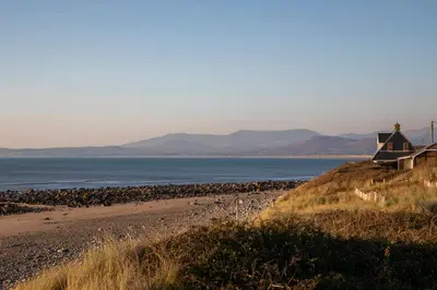 a house on a hill next to a beach at Allt y Mor in Harlech