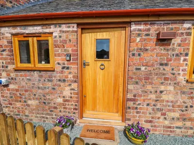 a wooden door on a brick house with flowers at The Tractor Shed in Oswestry