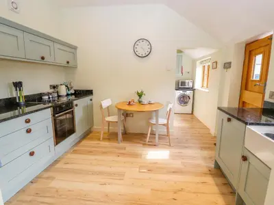 a kitchen with a table and a clock on the wall at The Tractor Shed in Oswestry