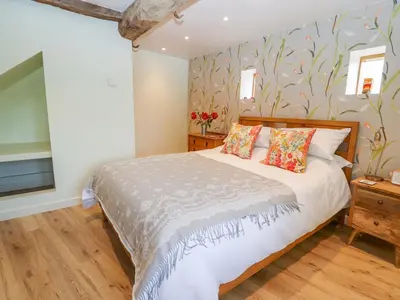 a bedroom with a bed with a floral wallpaper at The Tractor Shed in Oswestry