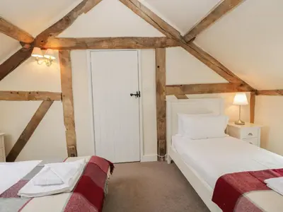 two beds in a room with wooden beams at The Old Barn in Hereford