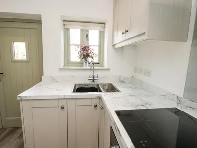 a white kitchen with a sink and a window at Rectory Cottage in Oswestry