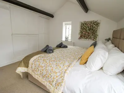 a bedroom with a large white bed with pillows at Rectory Cottage in Oswestry