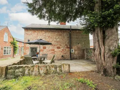 a patio with a table and an umbrella at Rectory Cottage in Oswestry