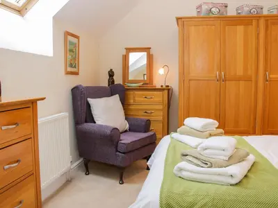 a bedroom with a chair and towels on a bed at Southdown in Much Wenlock