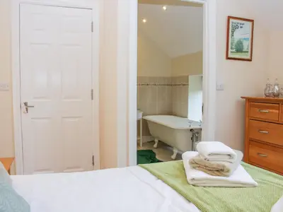 a bedroom with a bed and a tub and a bathroom at Southdown in Much Wenlock