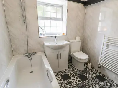 a bathroom with a tub and a sink and a toilet at The Stable Cottage in Llanbedr