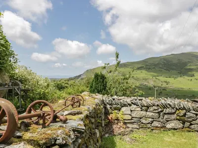 a stone wall with rusted equipment on top of it at The Stable Cottage in Llanbedr