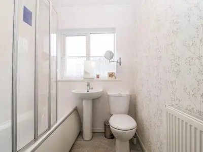 a white bathroom with a toilet and a sink at Clyd Fan in Harlech