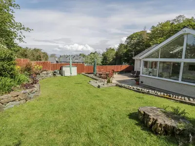 a backyard with a house and a lawn with a log at Clyd Fan in Harlech