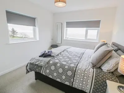 a bedroom with a bed and two windows at Hendre Wylan in Barmouth