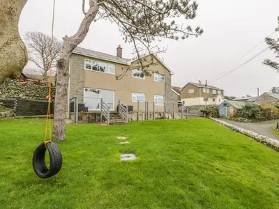 a tire swing hanging from a tree in a yard at Hendre Wylan in Barmouth