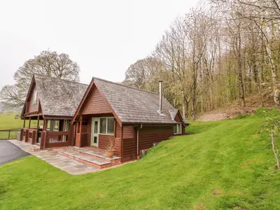 a small wooden house on a grassy hill at Pines Pitch in Knighton