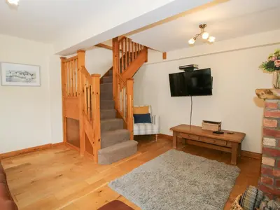 a living room with a staircase and a tv at Old Hall Barn 2 in Church Stretton