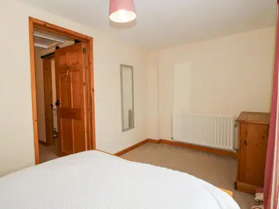 a bedroom with a white bed and a wooden door at Old Hall Barn 2 in Church Stretton