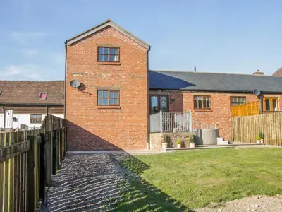 a brick house with a fence in front of it at Old Hall Barn 2 in Church Stretton