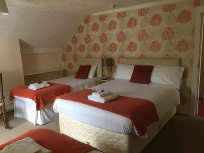 a bedroom with two beds with red and white sheets at The New Inn in Oswestry