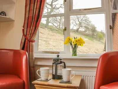 a table with two chairs and a window with flowers at Ragleth Place Lodge in Church Stretton