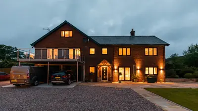 a large house with a truck parked in front of it at Woodland View Holiday Apartment in Llanwrda