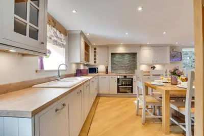 a kitchen with white cabinets and a wooden table at 4 Bed in Bala oc-bow66 in Bala