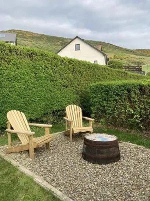 two wooden chairs and a coffee table in a yard at 3 Bed in Aberystwyth oc-bow115 in Aberystwyth