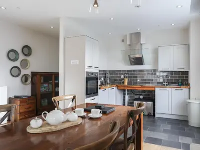 a kitchen with a wooden table and a kitchen with white cabinets at Harlech Apartments - Bendigeidfran in Harlech