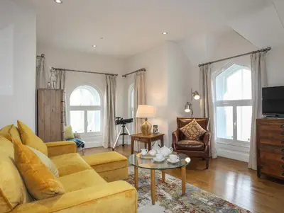 a living room with a yellow couch and a table at Harlech Apartments - Gwern in Harlech