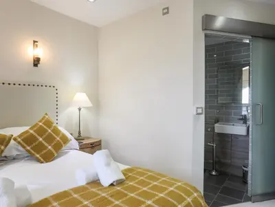 a bedroom with a bed and a bathroom with a shower at Harlech Apartments - Gwern in Harlech