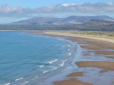 an aerial view of a beach with mountains in the background at Harlech Apartments - Matholwch in Harlech