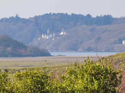 a castle on top of a hill near a body of water at Big House in Llandecwyn