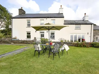 a table and chairs with an umbrella in front of a house at Big House in Llandecwyn