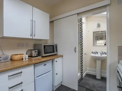 a kitchen with white cabinets and a sink at Little House in Llandecwyn