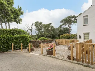 a fence with flowers in a yard next to a house at Little House in Llandecwyn