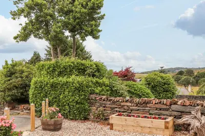 a garden with a stone wall and flowers at Little House in Llandecwyn