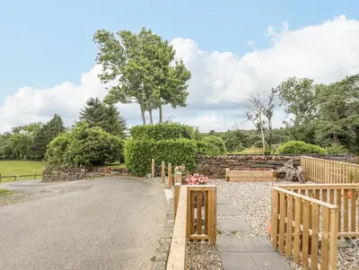 a driveway with a wooden fence and a tree at Little House in Llandecwyn
