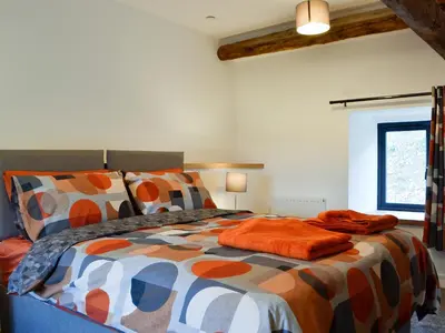 a bedroom with a bed with a colorful comforter at Pistyll Gwyn in Llanwrthwl