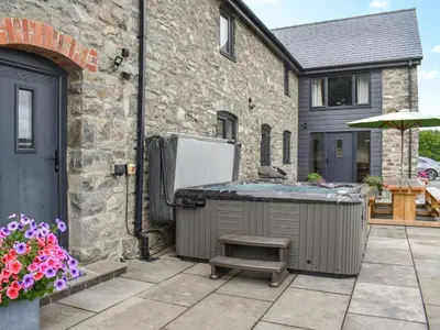 a backyard with a hot tub and a house at Pistyll Gwyn in Llanwrthwl