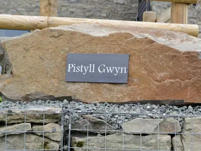 a sign on top of a large rock at Pistyll Gwyn in Llanwrthwl