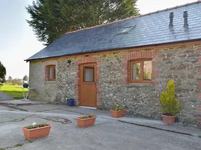 a small stone house with potted plants in front of it at Hen Llaeth - Uk11209 in Cwrt-newydd