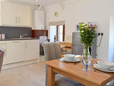 a kitchen with a table with a vase of flowers on it at Hen Llaeth - Uk11209 in Cwrt-newydd