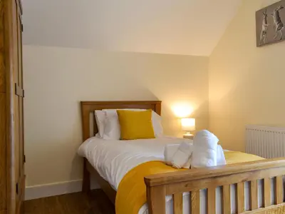 a bedroom with a bed with yellow and white pillows at Tyddyn Eli in Llangwm