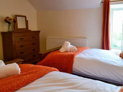 a bedroom with two beds with towels and a dresser at Tyddyn Eli in Llangwm