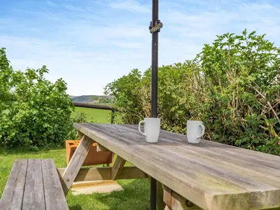 a wooden picnic table with two white mugs on it at Cambrian Mountain View in Llanafan-fawr