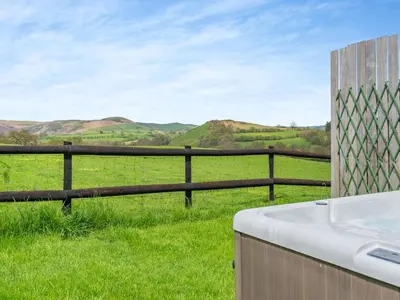 a bath tub in front of a fence with a field at Cambrian Mountain View in Llanafan-fawr