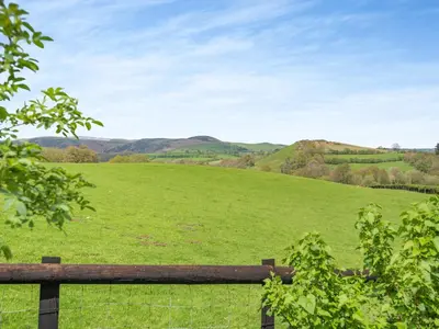 a field of green grass with a wooden fence at Cambrian Mountain View in Llanafan-fawr
